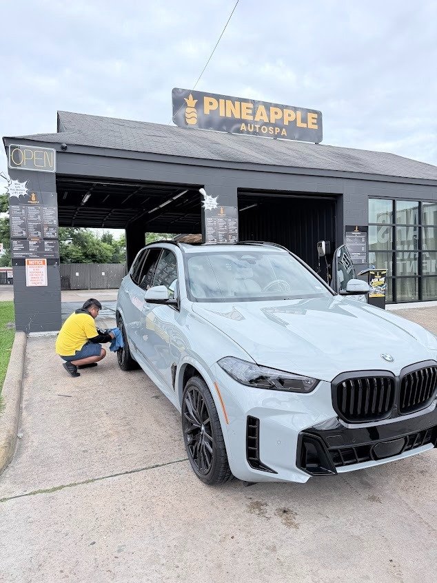 Detailer working panel by panel on a BMW X5 at Pineapple Autospa, Houston