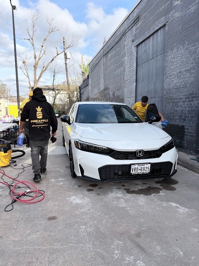 Detailer finishing the interior of a Honda Civic at Pineapple Autospa