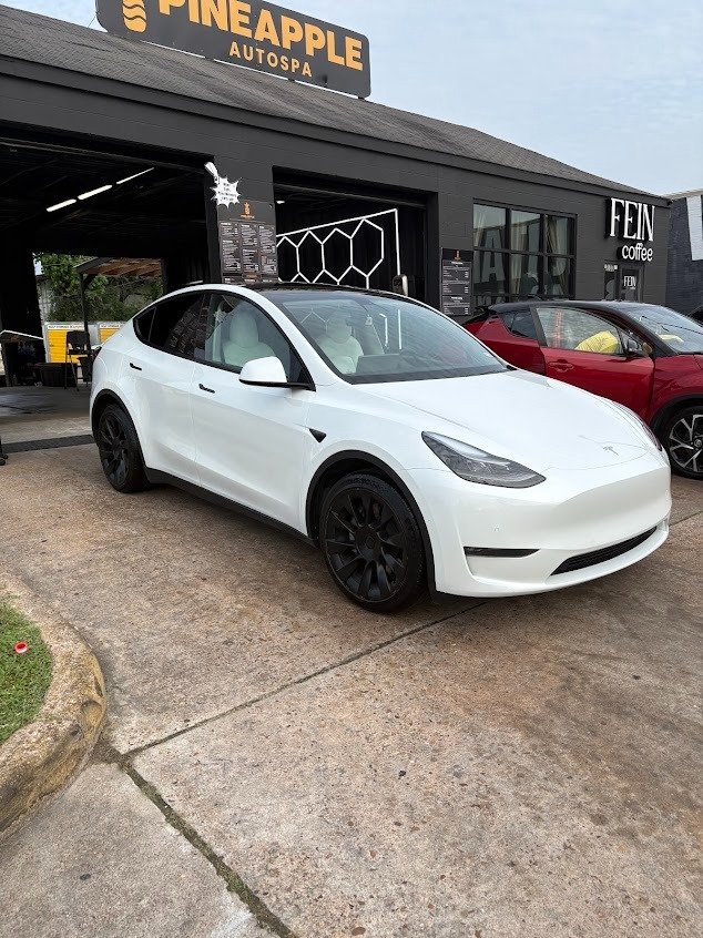 Tesla Model Y outside Pineapple Autospa Montrose with the on-site FEIN coffee café