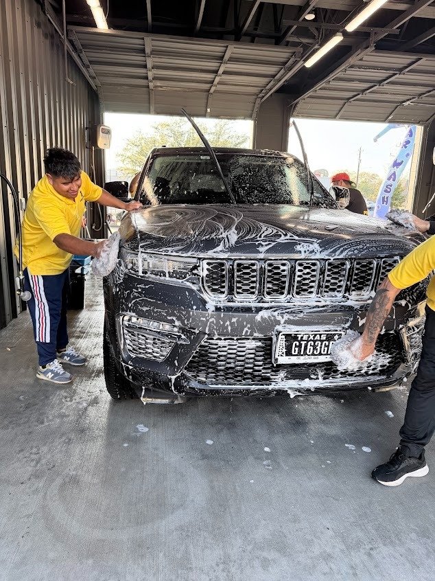 Two detailers hand washing a Jeep Grand Cherokee at Pineapple Autospa